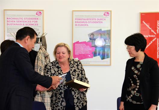 Die Präsidentin der HSD ist in der Mitte des Bildes, sie übergibt dem links neben ihm stehenden Prof. Dr. Xu Yongbin (Dekan der „School of Foreign Studies“) ein Buch als Gastgeschenk, die Vizerektorin der UIBE, Prof. Dr. Wen Jun, sieht dabei zu.